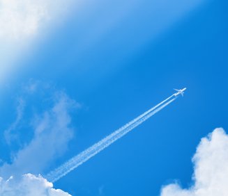 Airplane,Flying,In,The,Blue,Sky,Among,Clouds,And,Sunlight