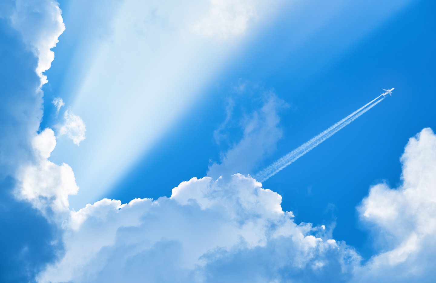 Airplane,Flying,In,The,Blue,Sky,Among,Clouds,And,Sunlight
